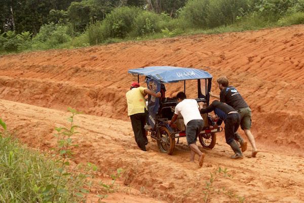 Ryan helping push a mototaxi stuck in the mud - Amazon Jungle, Peru