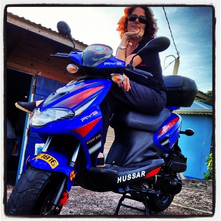 Nora Dunn on a blue scooter in Grenada