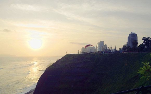 cliffside view over the ocean in Lima with paraglider taking off at sunset 